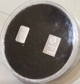 Two small 1 gram bars of Platinum encased in a display with a dark background