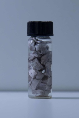 2 grams of small, moderately tarnished Sodium chunks in a bottle filled with mineral oil.