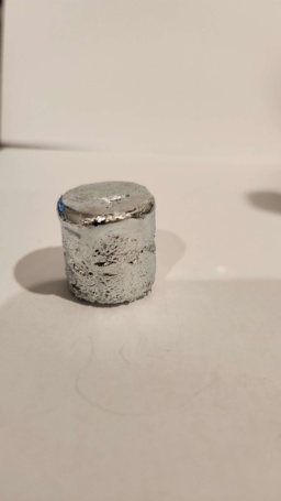 Three separate samples of Gallium. 1: "Rescue mission of gallium stuck in a tube." 2: "Gallium trying to 'escape' its cube (pressure from heat)." 3: "1g of gallium melted and completely covered bottle during transit."