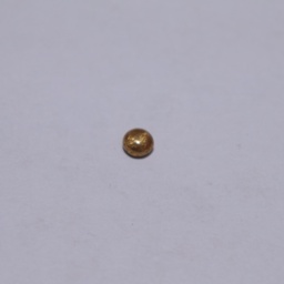 1 gram bead of Gold resting on a smooth surface