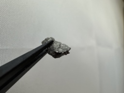 Tiny piece of Holmium metal. Some parts are slightly oxidized, some are shiny.