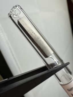 1 gram sample of Lutetium metal in an ampoule. This shiny sample was manufactured in the shape of a tall square prism.