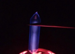 One larger and one smaller ampoule of Hydrogen gas on top of a plasma globe, glowing a purple-blue color