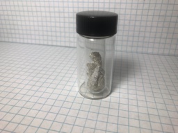 Super sparkly crystals of toxic Cadmium metal in an ampoule, which itself is in a bottle. This sample has a subtle brassy sheen, probably because of oxidation.