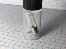 1 gram of Cesium metal in a sealed ampoule. Cesium is an extremely reactive, slightly brassy gold metal with a melting point a little above room temperature.