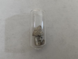 One tiny, and two medium chunks of Strontium metal in an ampoule. Most of the surface is slightly tan from oxidation, with some shiny parts coming through.