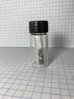 Small shiny chunks of brassy Cerium metal in an ampoule, which itself is in a small bottle. Cerium is a rare-earth metal and should not be confused with the alkali metal |cs|.