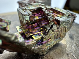 Macro photograph of a bismuth crystal showing the detailed stair-step structure and rainbow color