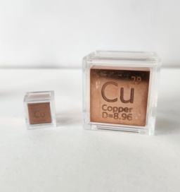 2 polished copper cubes, both in clear cases: 1 cm cube on the left, 1 inch cube on the right