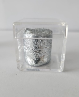 A chunk of extremely shiny Gallium metal inside a clear box with a clear lid