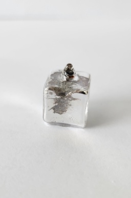 Potassium metal safely encased in a cube-shaped glass ampoule about 1 cubic cm in size