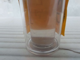 A sample of Gallium in a vial itself inside a bottle. Orange construction paper is fixed on the outer bottle with the symbol "Ga" and the electron shell.