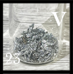 Small, silvery, poorly formed crystals of Vanadium metal in a bottle