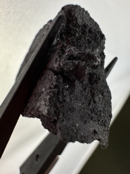 A large, dark, amorphous chunk of high-purity crystalline Boron. Small flecks are shiny.