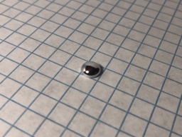 1 gram Mercury "bead." Mercury is a liquid metal at room temperature, but its remarkably high surface tension allow it to remain in its shape, though somewhat flattened.