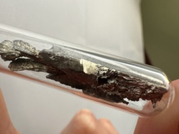 Ytterbium metal chunk in an ampoule. The slightly gold hue characteristic of Ytterbium is clearly visible.