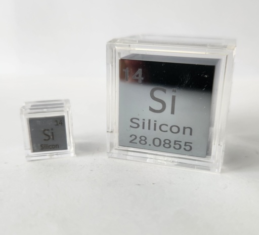 Two extremely polished and shiny Silicon cubes: a 1 cm cube on the left, and a 1 inch cube on the right. Both are in clear cases