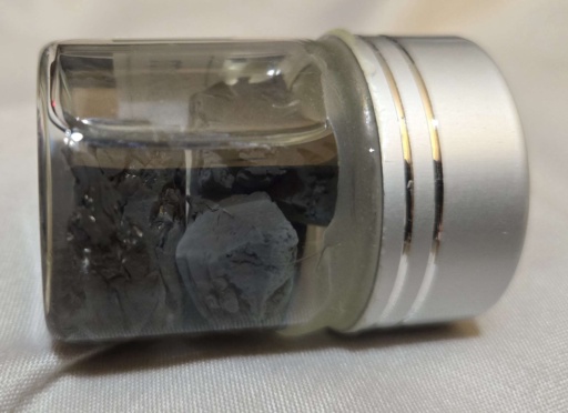 Heavily tarnished chunks of Calcium metal under oil in a bottle. Calcium is difficult to keep shiny.