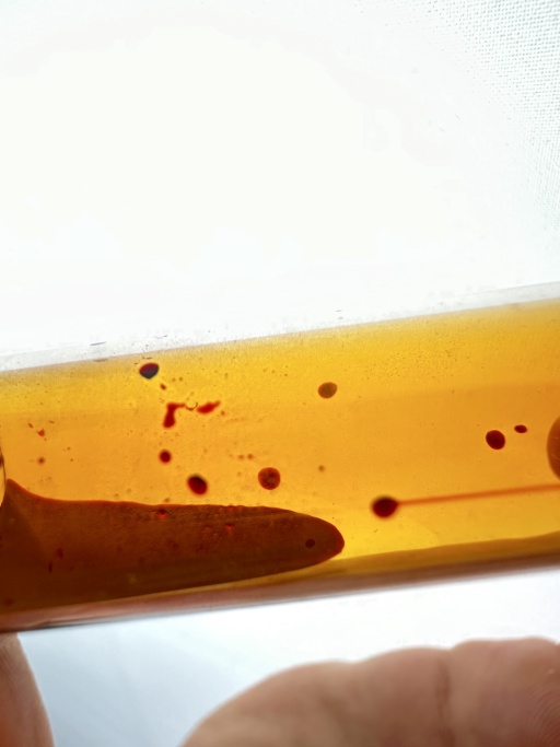 A small amount of liquid Bromine flowing in a tilted ampoule.