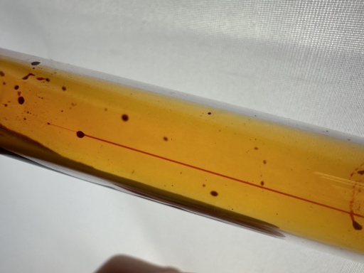 A small amount of liquid Bromine flowing in a tilted ampoule.