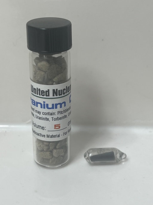 Small piece of depleted Uranium metal, beside a bottle of Uranium ore chunks