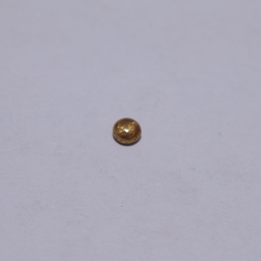 1 gram bead of Gold resting on a smooth surface