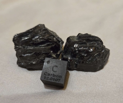 A cube and two irregular chunks of Carbon