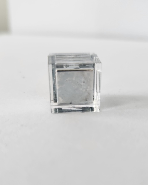 A sample of Gallium metal that has filled a tiny clear cube case