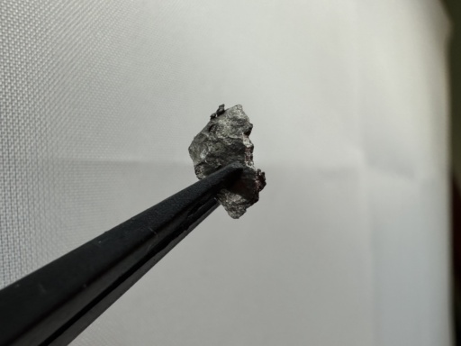 Tiny piece of Holmium metal. Some parts are slightly oxidized, some are shiny.