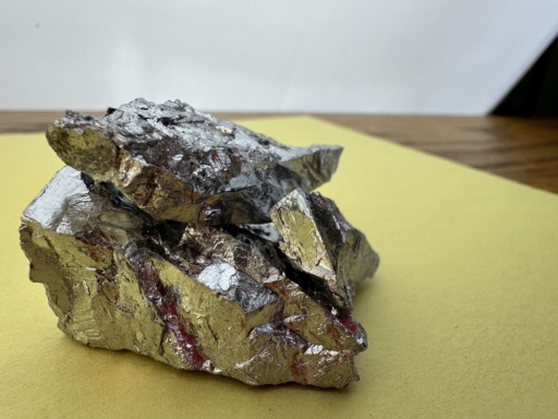 Chunks of Chromium metal on a sheet of yellow construction paper.