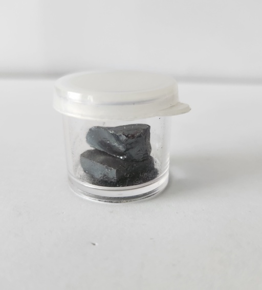 Chunks of Selenium in a clear container with a translucent lid