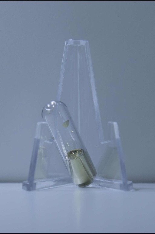 1 gram of solidified Cesium in an ampoule, resting on a clear folding stand