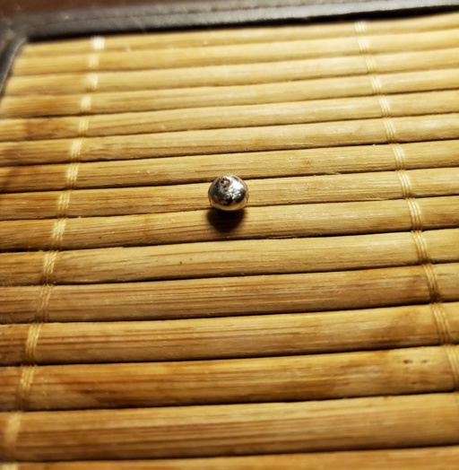 Small bead of shiny Ruthenium on a bamboo (or wooden) platter