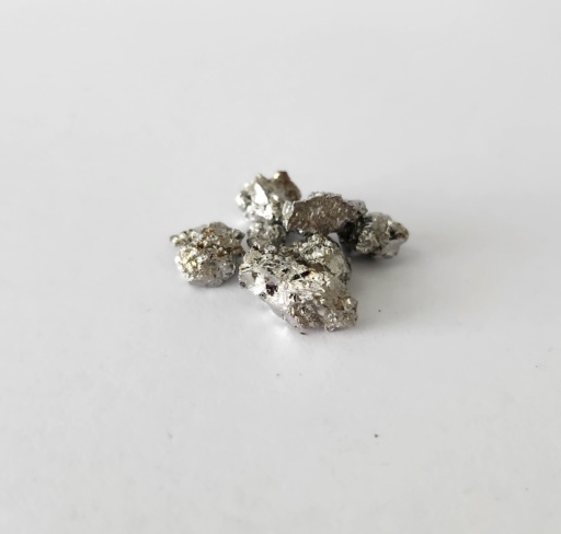 Very shiny small irregular chunks of Manganese metal with a slightly gold hue