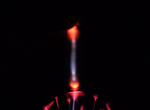 Neon gas in an ampoule on top of a plasma globe, glowing a characteristic red-orange color