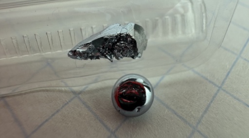 Macro photograph of a 1 gram Osmium metal crystal showing its structure, and a smooth 1 gram bead. Osmium has a subtle silvery-blue hue.