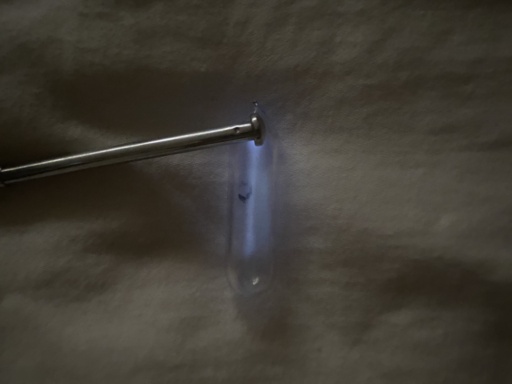 Oxygen in an ampoule. Normally an invisible gas, Oxygen glows a faint white-blue when put under high voltage.