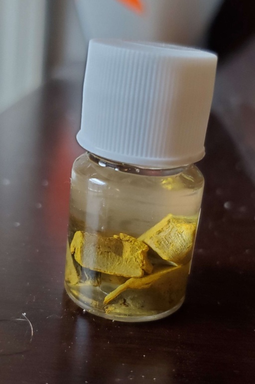 Heavily oxidized pieces of Europium metal under oil in a bottle. The oxidation is a bright yellow color.