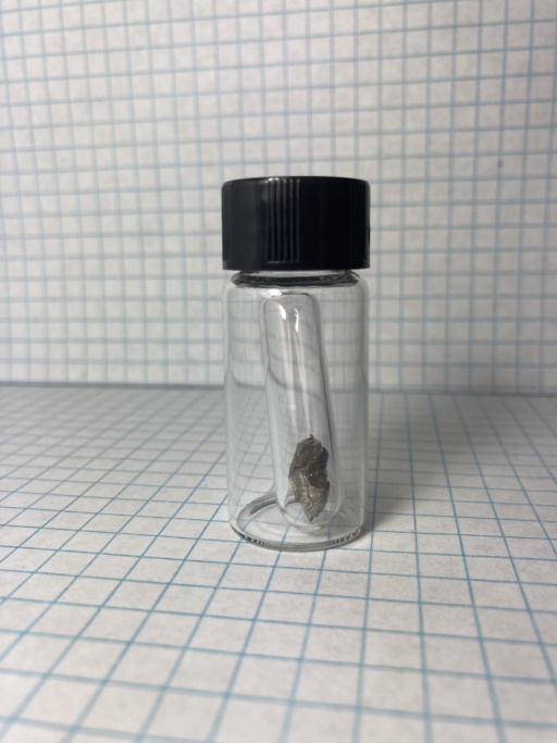 Small shiny piece of Lanthanum metal, in an ampoule which itself is in a small bottle.