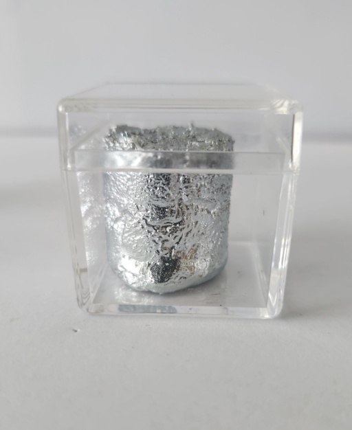 A chunk of extremely shiny Gallium metal inside a clear box with a clear lid