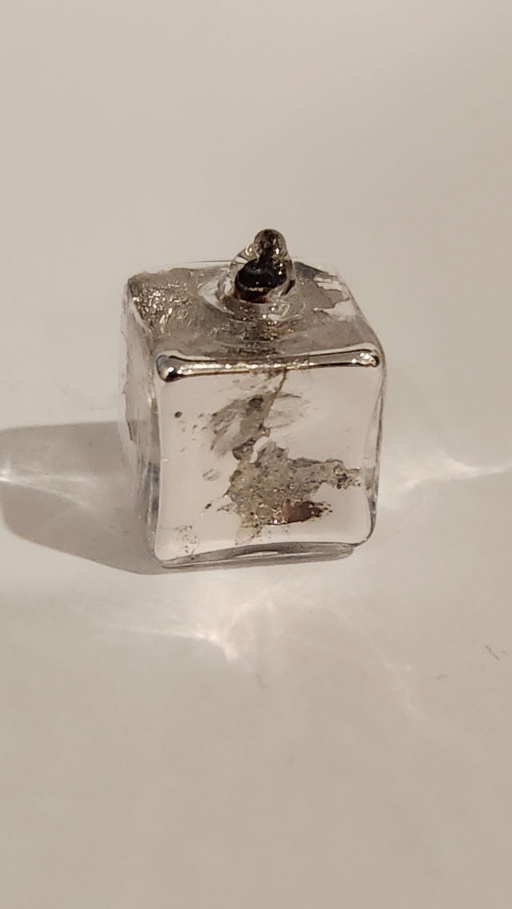 Potassium metal safely encased in a cube-shaped glass ampoule about 1 cubic cm in size