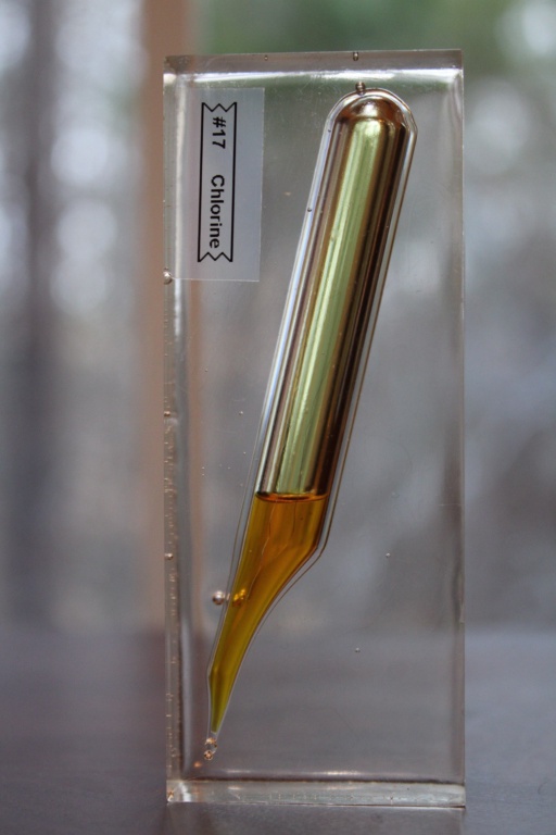 Ampoule of liquid Chlorine encased in a clear acrylic block. Chlorine is normally a gas, but the sample is roughly under 8 times normal atmospheric pressure which allows it to liquify. The characteristic evil yellow color of liquid Chlorine is clear to see.