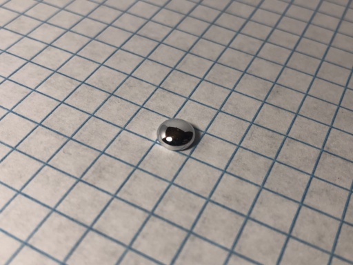 1 gram Mercury "bead." Mercury is a liquid metal at room temperature, but its remarkably high surface tension allow it to remain in its shape, though somewhat flattened.